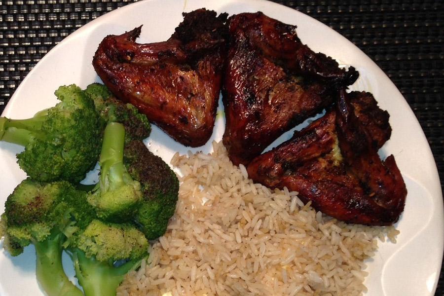 Alitas de pollo jerk con arroz y brócoli.