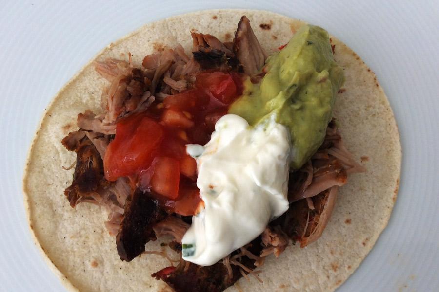 Tostada mexicana con frijoles refritos, cochinita pibil, salsa, guacamole y nata agria.