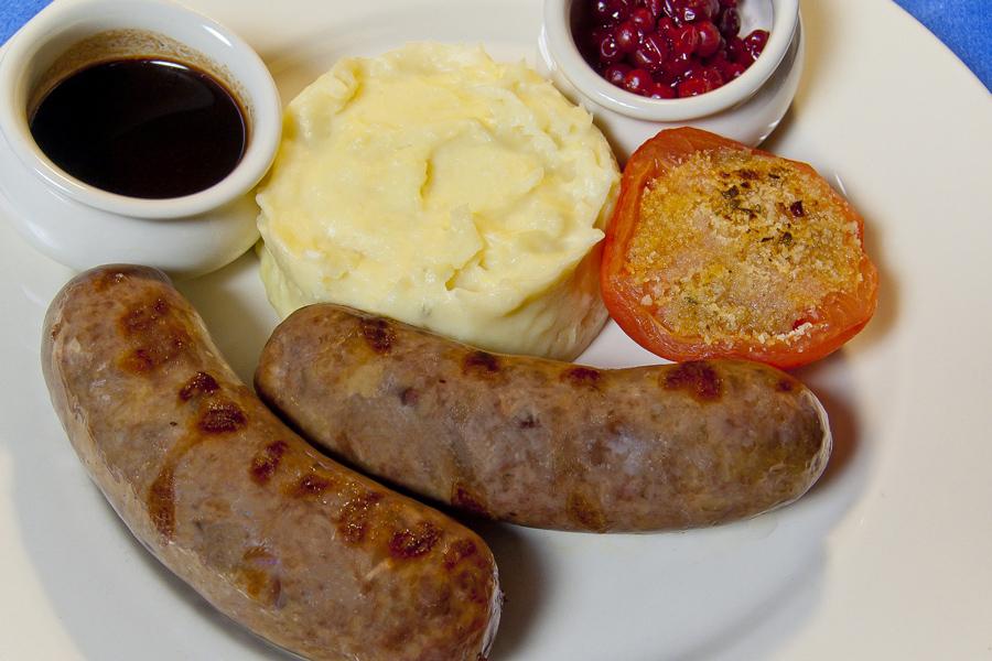 Salchichas de venado con puré de patata, salsa marrón y salsa de arándanos.