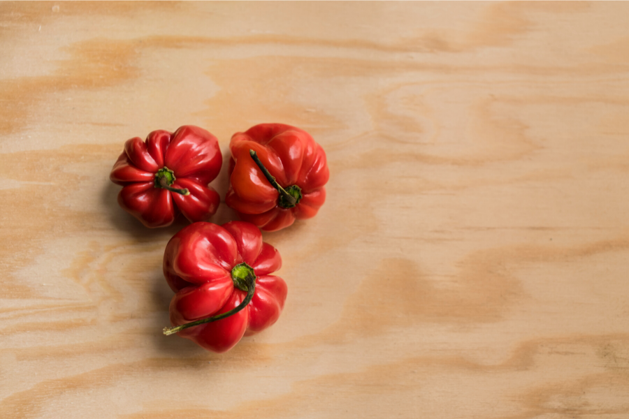 Tres chiles habaneros sobre tabla de madera.