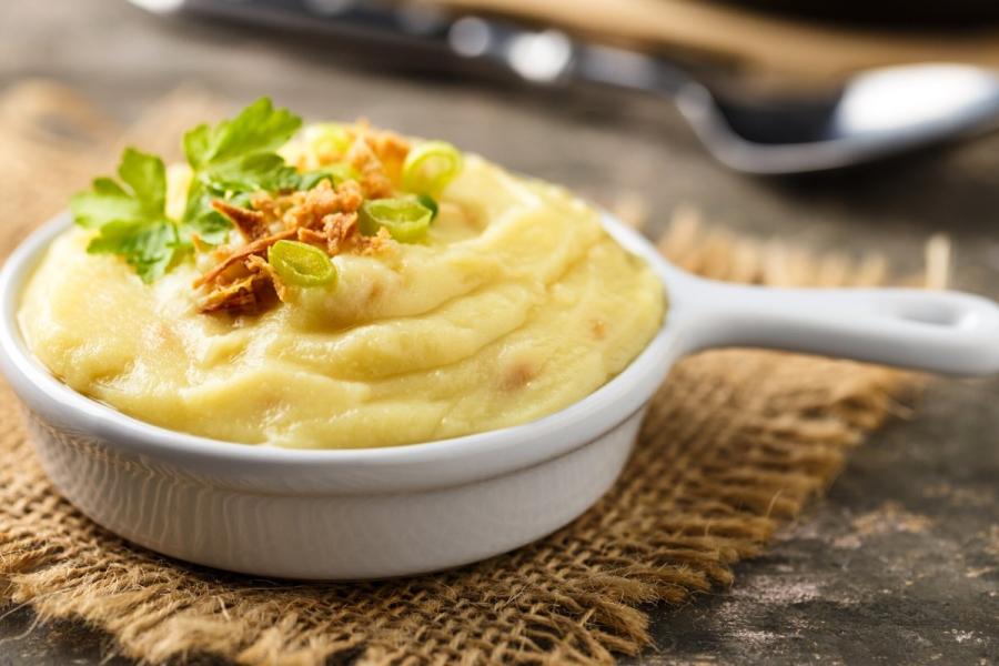 Un cacillo con puré de patata con cebolla crujiente encima.