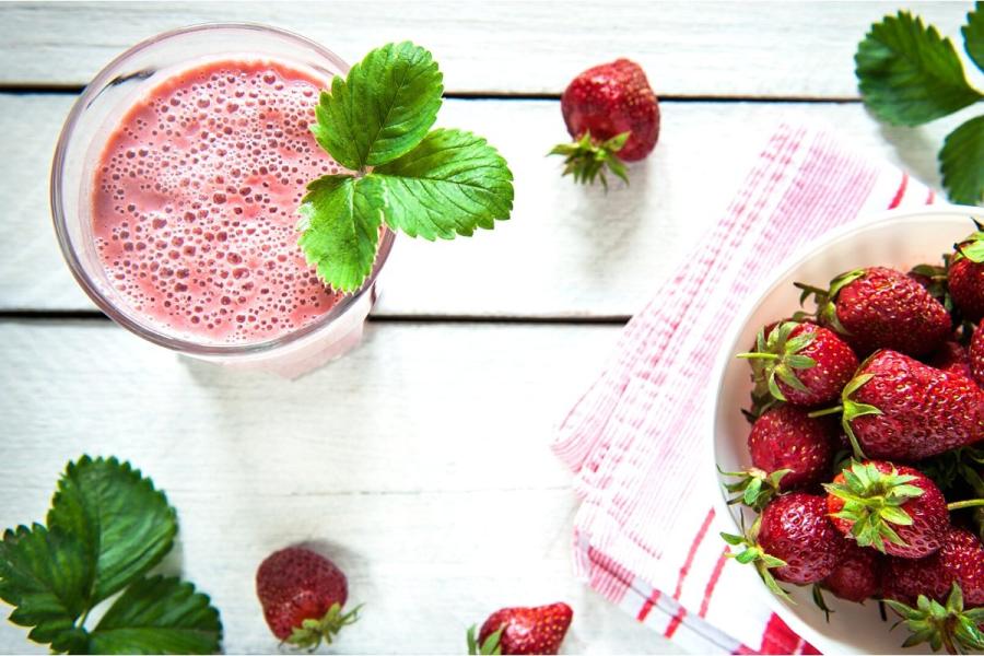 Zumo de fresas con leche y fresas en una mesa de madera.