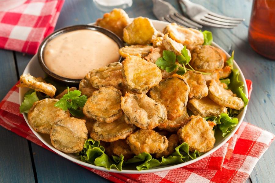 Rodajas de pepinillos en vinagre, rebozadas y fritas, con salsa para mojar.