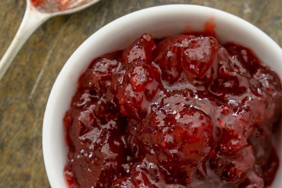 Mermelada de fresa y piña en un cuenco con una cuchara al lado.