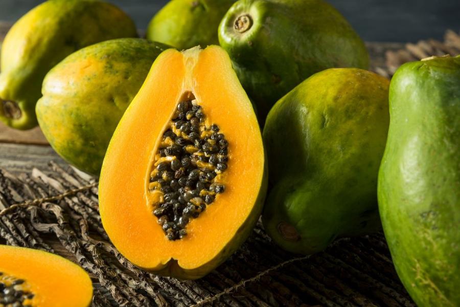 Una papaya cortada por la mitad entre papayas enteras.
