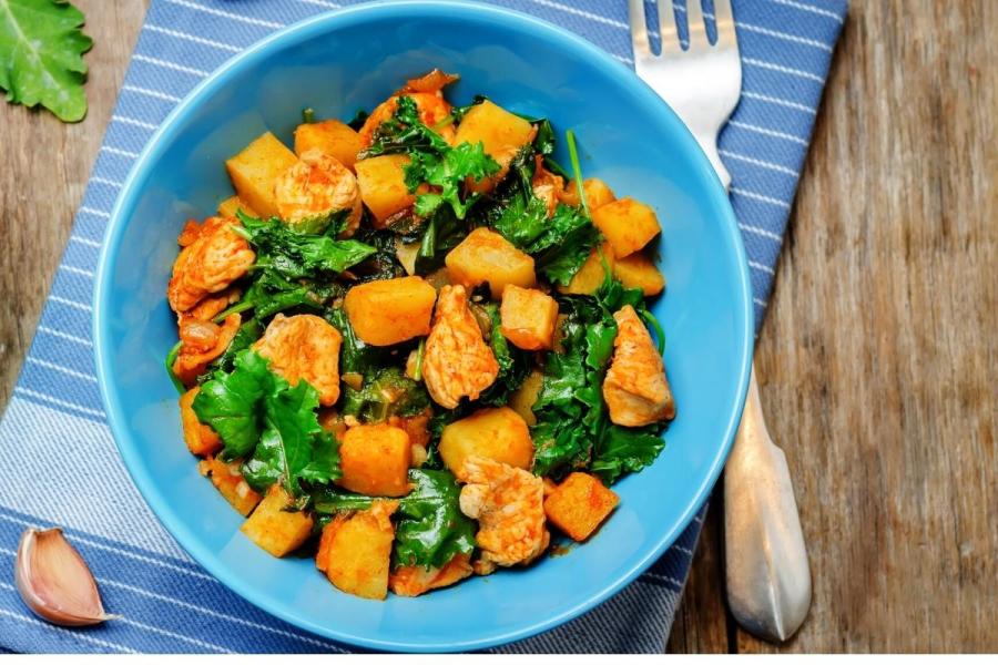 Guiso de pollo con batata y hojas verdes.