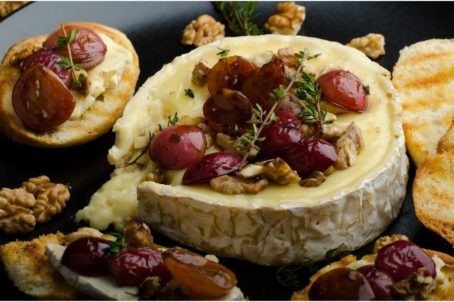 Queso brie hornado con nueces y uvas.