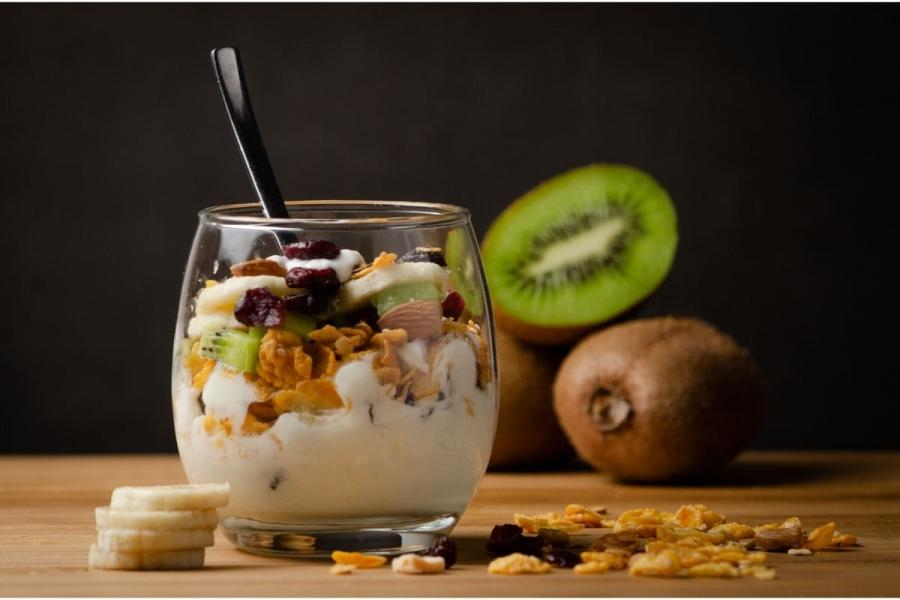 Una copa de kiwi, granola y yogur en vaso de globo.