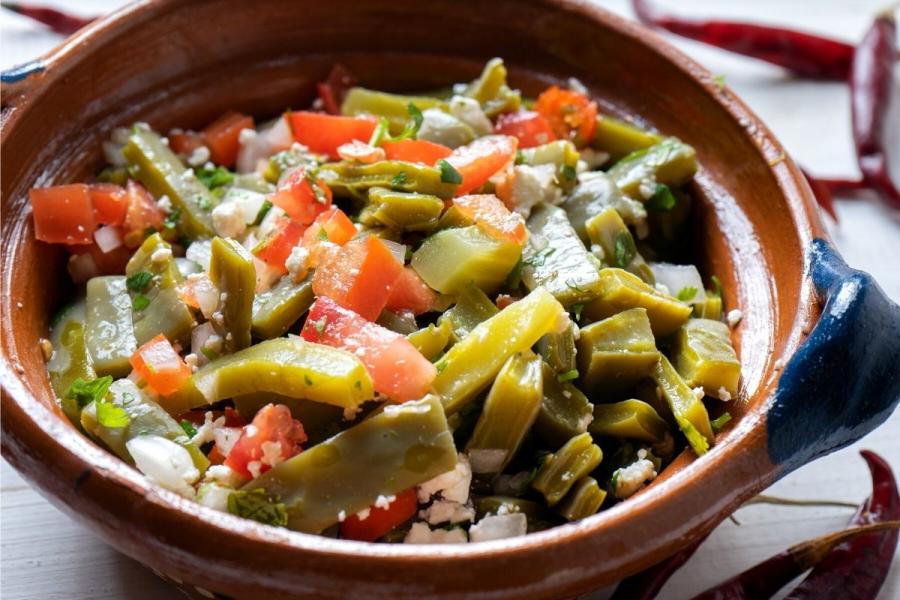 Ensalada de nopales y tomate en un cuenco de loza rústica.