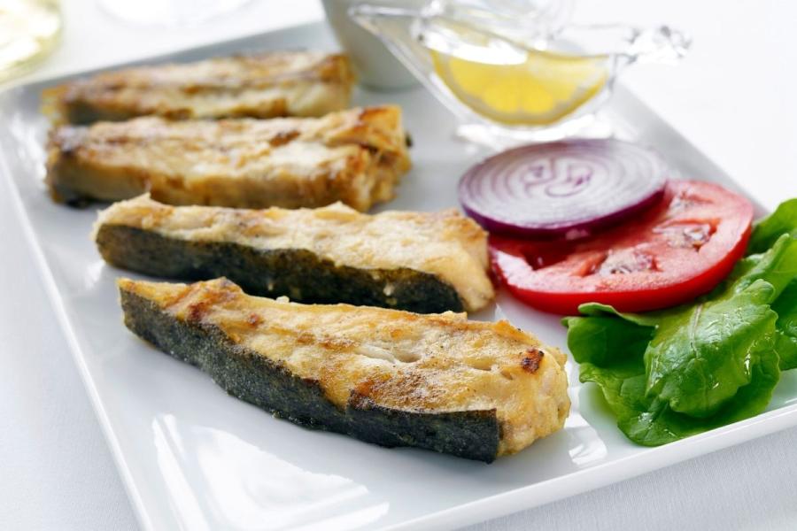 Rodajas de pescado al vino blanco con salsa servida aparte en salsera.