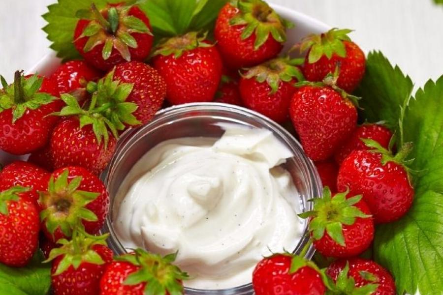 Un cuenco de crema de queso a la vainilla rodeado de fresas frescas.