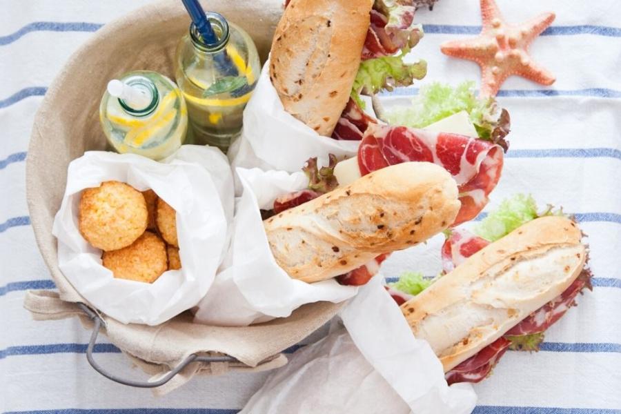 Bocadillos, comida y bebida para disfrutar de un picnic en la playa.