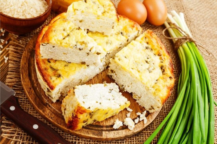 Budín de arroz y requesón ya hecho, con alguno de los ingredientes alrededor.
