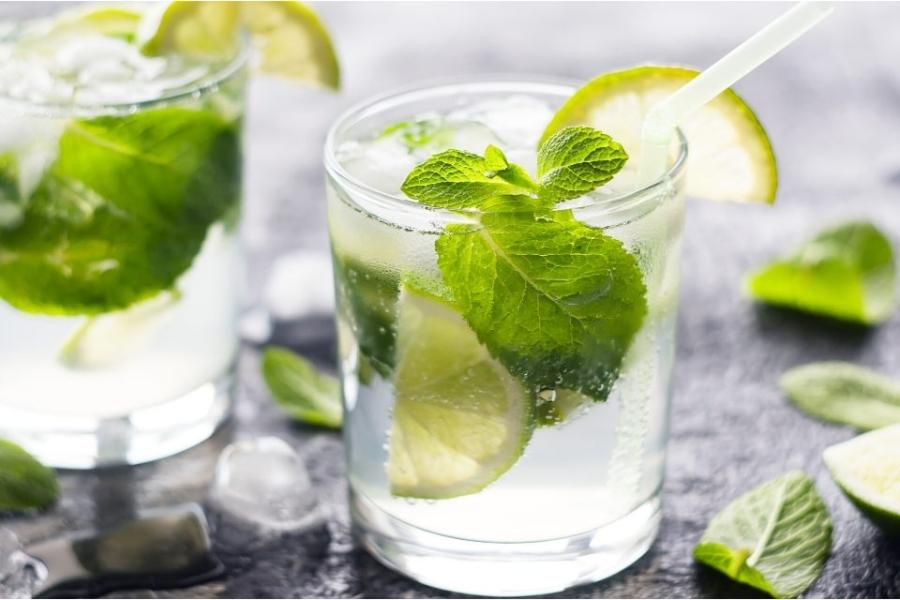 Dos vasos con mojitos, combinados con ron, azúcar, zumo de lima, menta y agua con gas.