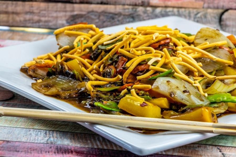 Un plato con fideos chinos y verduras salteados con salsa de soja negra.