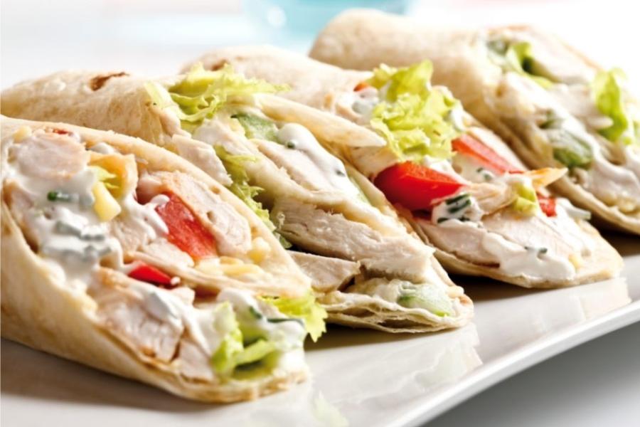 Burritos de pollo y verduras cortados por la mitad en diagonal.