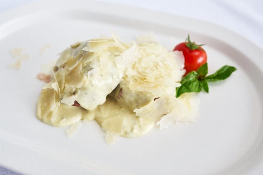Un plato con medallones de ternera cubiertos con salsa de puerro y queso.