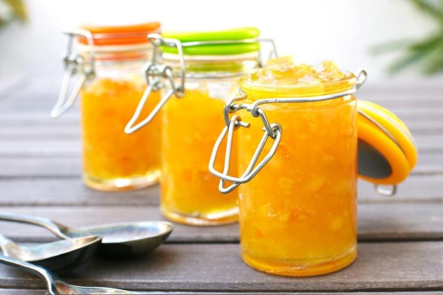 Tres recipientes de vidrio con mermelada de naranja.