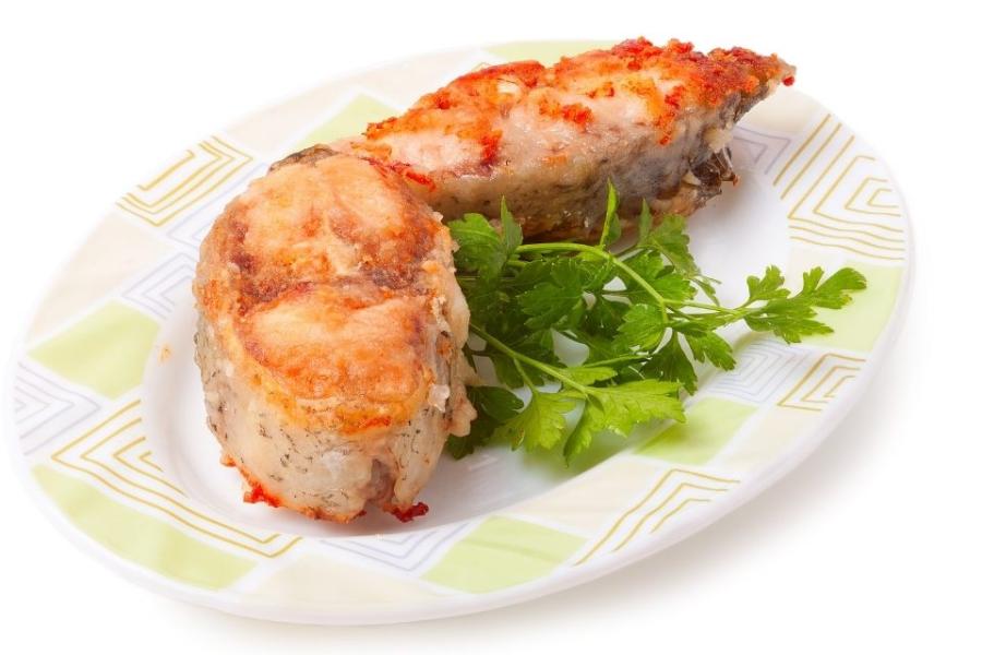 Un plado de rodajas de pescado con tomate decoradas con ramitas d eperejil.
