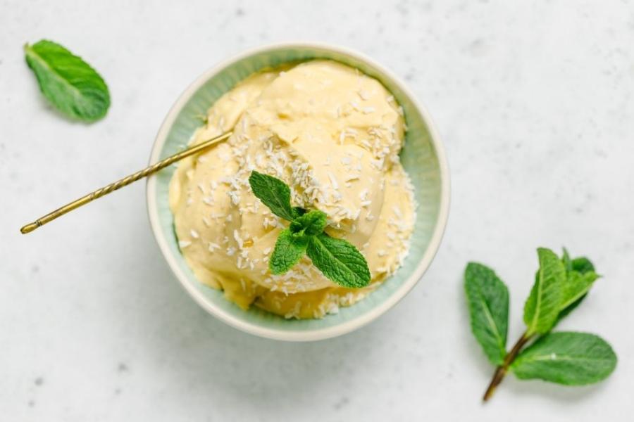 Helado de mango y leche de coco decorado con coco rallado y menta.