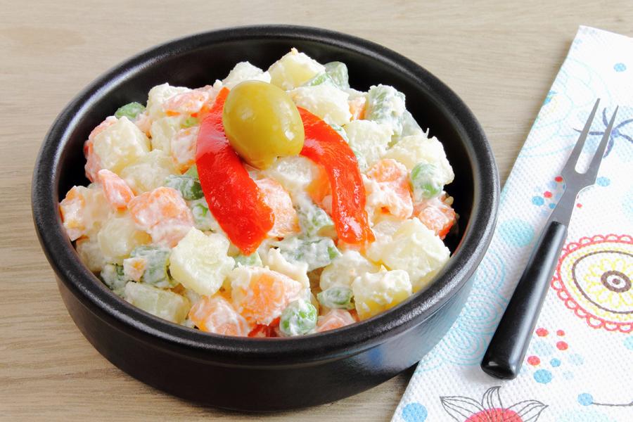 Ensaladilla con patata cocida, zanahoria,guisantes y pimiento morrón ligados con mahonesa.