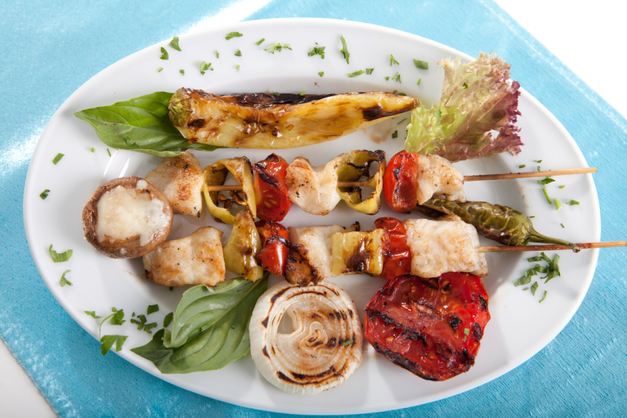 Pinchos de pescado acompañados de lechuga y hortalizas a la plancha.
