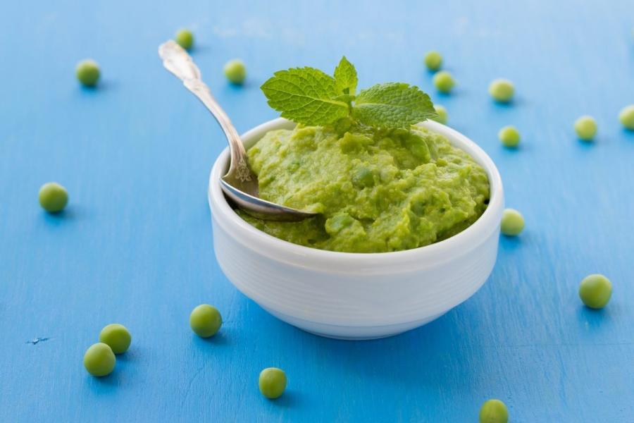 Un cuenco con puré de guisantes, decorado con hojas de menta.