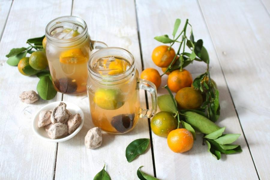 Zumo de lima calamansi, calamansis con hojas y ciruelas secas.