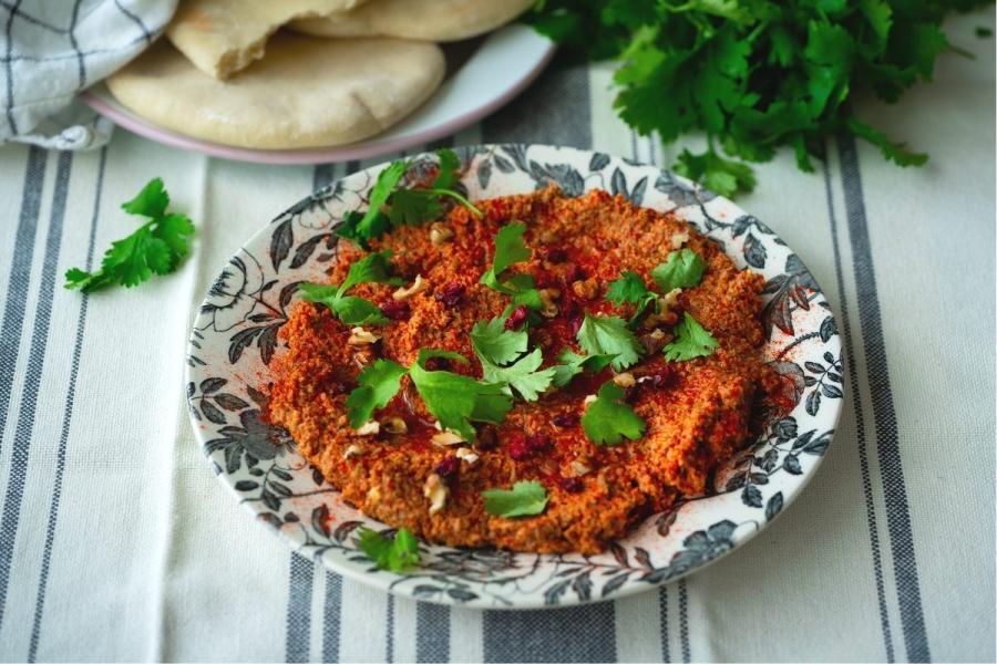 Un cuenco con muhammara decorada con perejil.