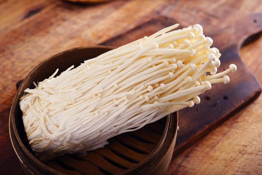 Setas de aguja de oro, o enoki, sobre madera.