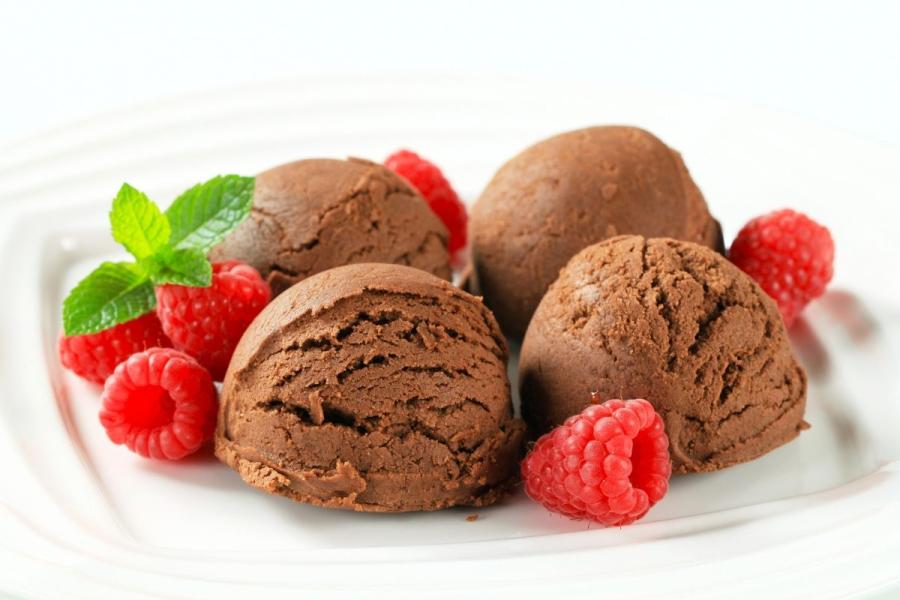 Helado de chocolate y almendras decorado con frambuesas frescas y hojas de menta.