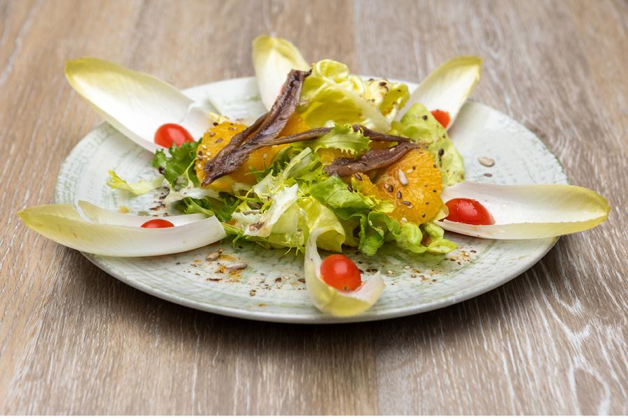 Ensalada de endibias con anchoas, tomate, naranja y lechuga.