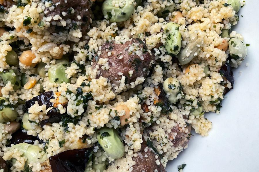 Detalle de una ensalada de cuscús con albóndigas de carne, habas tiernas, garbanzos cocidos y berenjena frita.