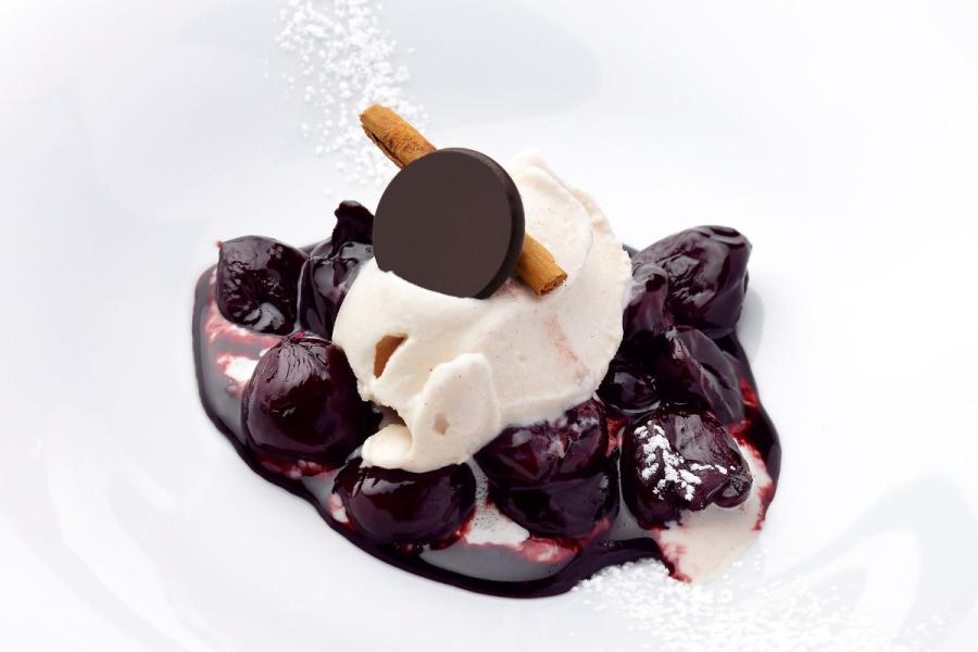 Cerezas al vino tinto acompañadas de helado, chocolate y canela en rama.