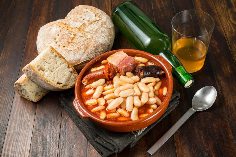 Un plato de fabada asturiana acompañado de sidra.