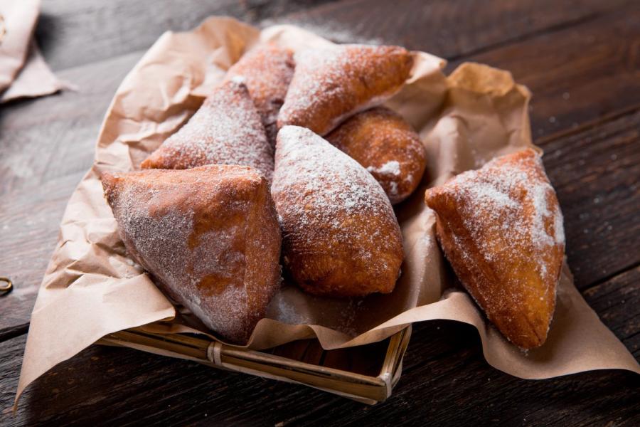 Una cesta forrada de papel con mandazi.