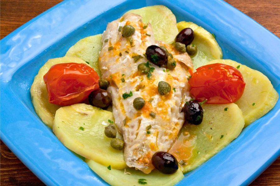 Filete de pescado cocido sobre lecho de patata cocida con vinagreta, alcaparras, aceitunas y tomates miniatura.