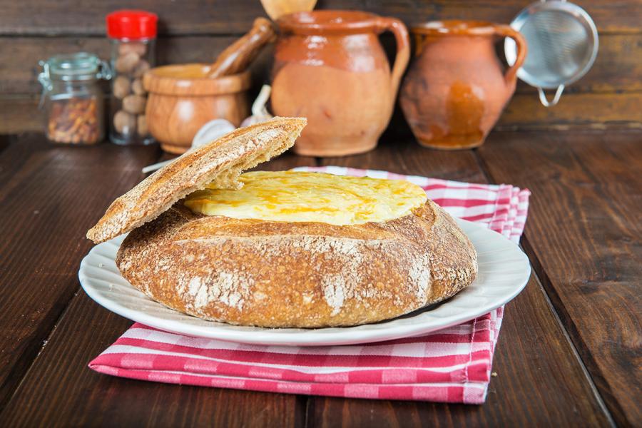 Besamel cremosa de bacalao gratinada con queso rallado en una hogaza de pan vaciada.