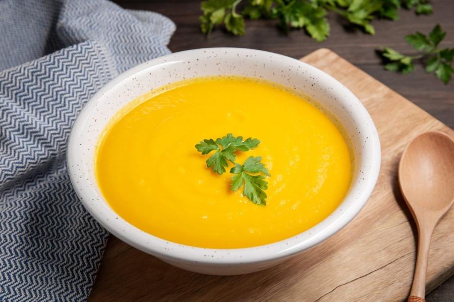 Un cuenco con crema de zanahoria al estilo francés adornada con perejil.