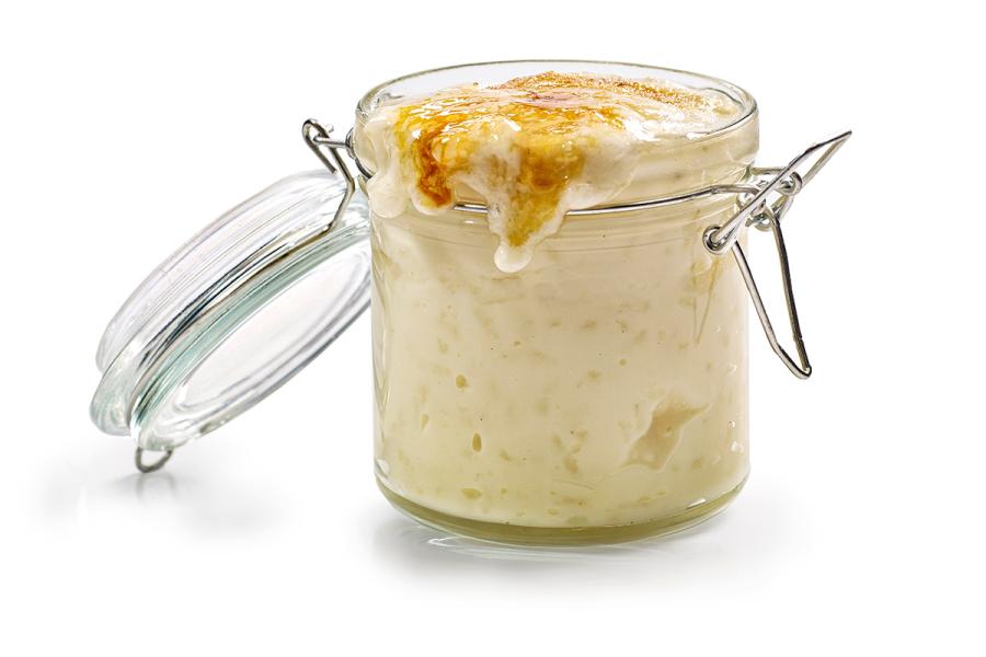 Un recipiente de vidrio con una porción de arroz con leche requemado.