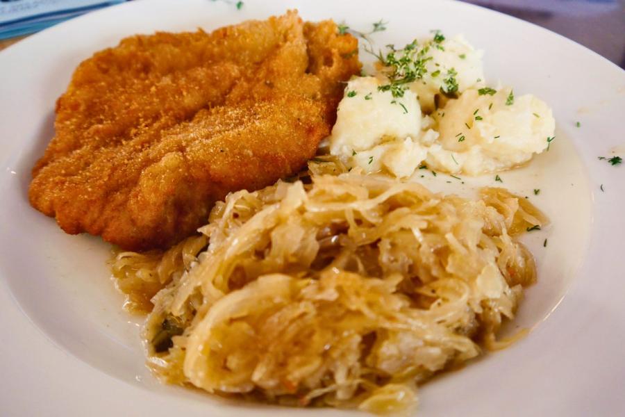 Un plato con un filete de cerdo empanado acompañado con repollo encurtido y puré de patata, al estilo polaco.