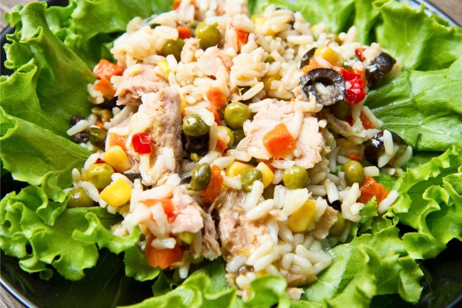 Ensalada de arroz con atún y verduras sobre un lecho de lechuga.