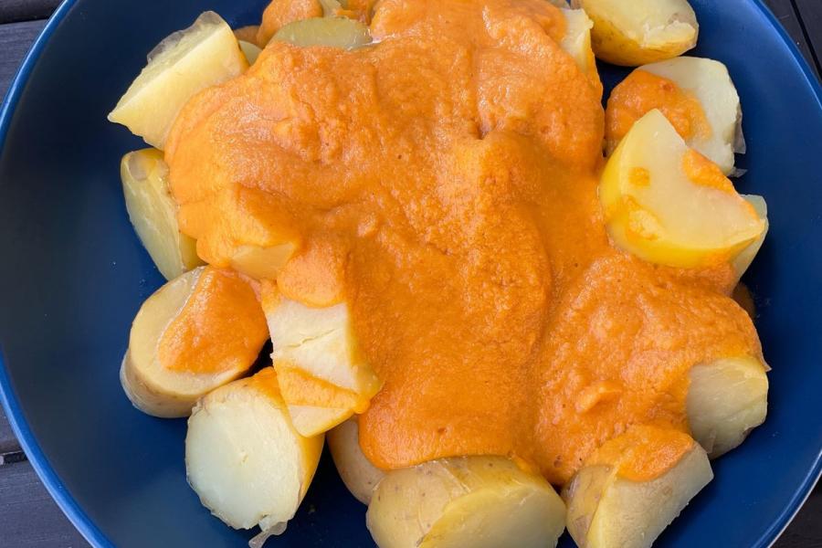 Ensalada de patata cocida con salsa de zanahoria en una fuente honda.