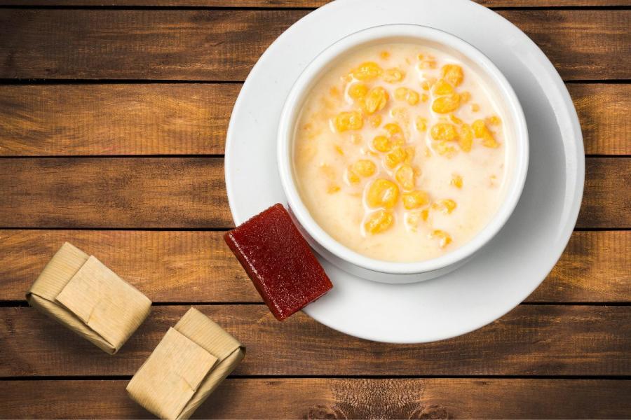 Un cuenco con mazamorra colombiana con dulce de guava al lado.