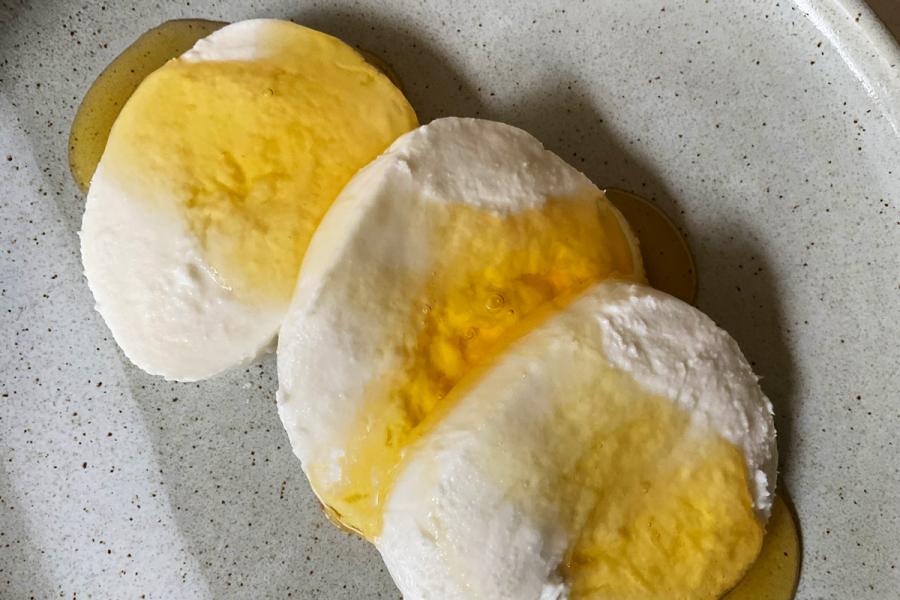 Un plato con tres rodajas de queso mozzarella cubierto con melado.