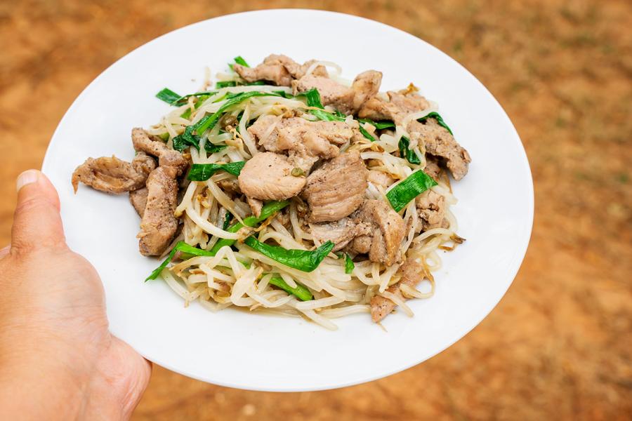 Un plato de cerdo salteado al estilo vietnamita con brotes de soja y cebollino chino.