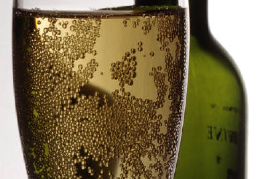 Una botella y una copa de vino espumoso.