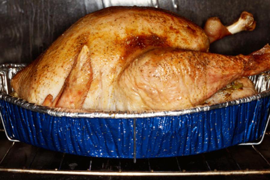 Un pavo asado en una fuente dentro del horno.