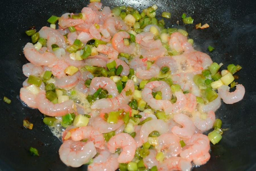 Ajetes y gambas friéndose en la sartén.