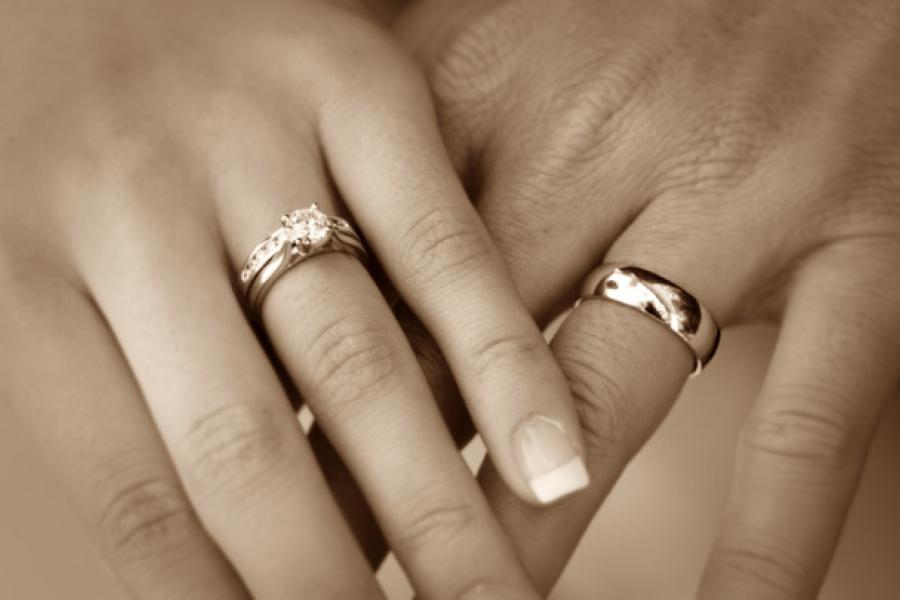 Dos manos cogidas llevando anillos de matrimonio.